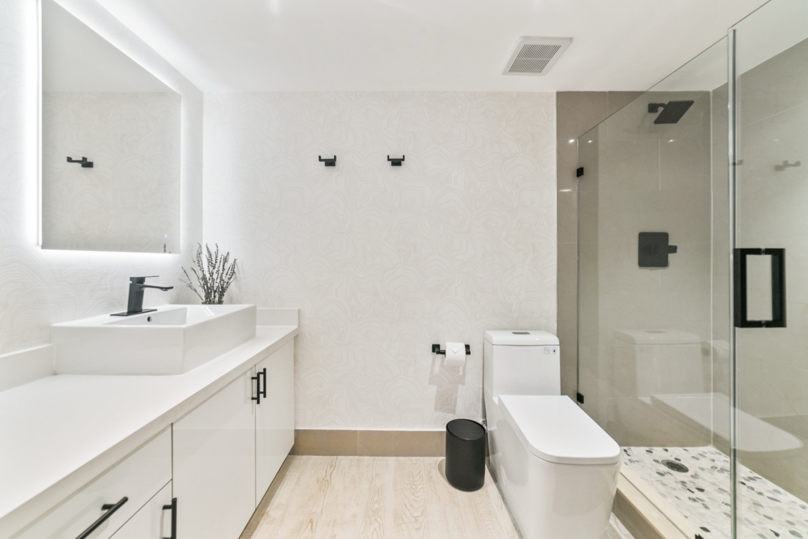 Bathroom with walk-in glass shower and backlit mirror